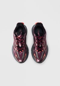 Baskets de sport avec une tige en mesh violette foncée et des accents métalliques. Présentent une semelle en caoutchouc noir, des détails orange et un système de laçage.