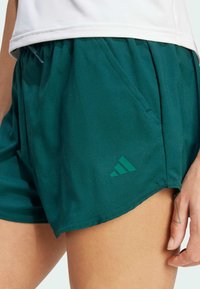 Teal sportieve shorts van lichtgewicht stof, met een elastische tailleband, zijzakken en een subtiele groene merklogo op de zoom.