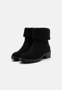 Bottines en daim noir avec un bord en velours noir, bout rond et semelle en caoutchouc épaisse pour une meilleure adhérence et stabilité.