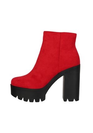 Rote Wildleder-Stiefelette mit einer schwarzen, klobigen Plattform und einem Absatz. Das Design weist eine glatte Textur und eine abgerundete Zehenpartie auf.