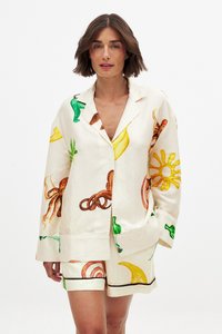 Linned sæt til afslapning med jakke med korte ærmer og shorts. Farverige frugt- og blæksprutteprints på en cremefarvet baggrund med sorte detaljer.