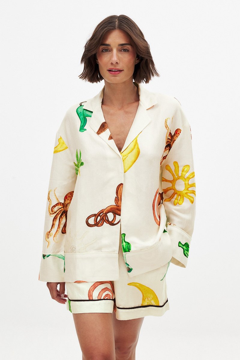 Linned sæt til afslapning med jakke med korte ærmer og shorts. Farverige frugt- og blæksprutteprints på en cremefarvet baggrund med sorte detaljer.