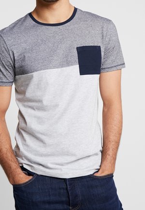 Šedé a námořnicky modré tričko s krátkým rukávem a kulatým výstřihem. Má vodorovný design s barevnými bloky a malou kapsičkou na prsou. Měkká textura látky.