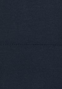 Tessuto blu navy strutturato con un leggero motivo a coste, con una finitura liscia e una leggera lucentezza. Le cuciture sono rifinite con precisione.