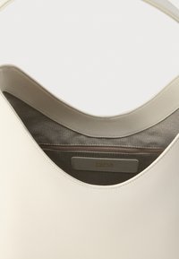 Crèmekleurige leren handtas met grijze voering, voorzien van een ritssluiting en een label met de tekst "Furla Since 1927".