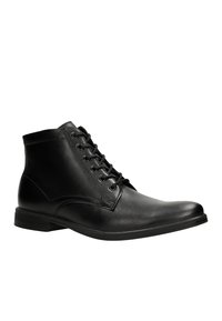 Stivaletti alla caviglia in pelle nera con punta tonda, design con lacci, texture liscia e dettagli di cucitura discreti. Suola piatta in gomma per stabilità.