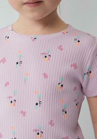 Lichtpaarse geribde t-shirt met kleine, kleurrijke patronen van karakters en vormen. Ronde halslijn en korte mouwen.
