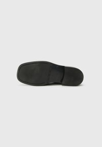 Black leather shoe sole with a smooth finish, rounded shape, and stitched trim. Features a flat, non-slip surface. Simple design.