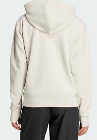 Sudadera con capucha color beige claro, con cordón ajustable, mangas largas y ribete acanalado. Tela suave con textura lisa y diseño sin costuras.