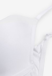 Fehér párnázott melltartókosár állítható vállpánttal és sima textúrájú anyaggal, közelről részletezve.