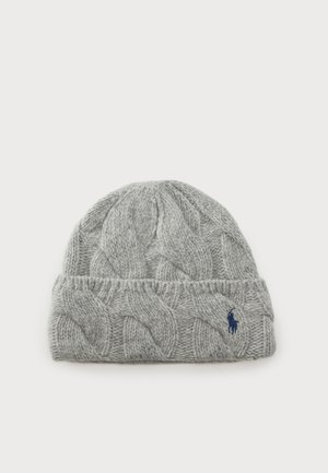 Bonnet en laine tricotée gris clair avec de larges motifs torsadés et un petit logo brodé bleu foncé sur le revers.