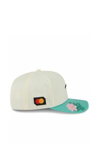 Cap mit einem cremefarbenen Oberteil, türkisfarbenem Schirm mit rosa Blumenstickerei und schwarzem sowie rotem Mastercard-Logo an der Seite.