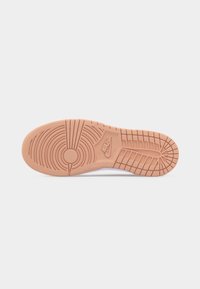 Εξωτερική σόλα ενός αθλητικού παπουτσιού Nike σε ανοιχτό καφέ χρώμα με κυκλικά και ορθογώνια σχέδια πέλματος και ορατό λογότυπο Nike στο κέντρο.