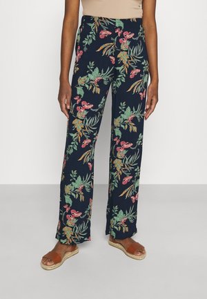 Pantalon à motif floral en tissu léger, avec un fond bleu marine et des motifs botaniques verts, roses et orange.
