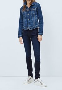 Jeansjacka i mörkblått med en strukturerad design, som har knappringning framtill, två bröstfickor och kontrasterande sömmar.