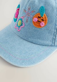 Hellblaue Denim-Baseballmütze mit mehrfarbigen gestickten Blumen- und Charakterdesigns. Verfügt über einen gebogenen Schirm und Kontrastnähte.
