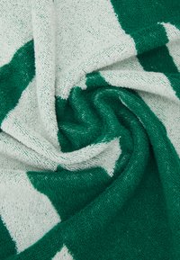Zelený a bílý pruhovaný ručník vyrobený z měkké, strukturované tkaniny, s střídajícími se velkými barevnými sekcemi v točitém designu.