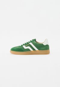 Sneaker verde din suede cu dungi albe și sireturi, având o talpă din cauciuc de tip gumă. Branding pe lateral în litere aurii. Design clasic.