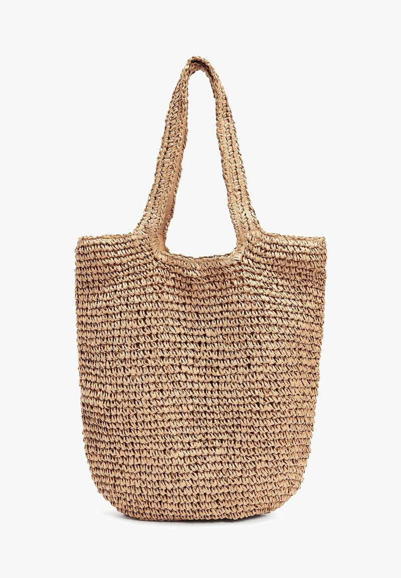Sac fourre-tout tissé en fibres naturelles, de couleur beige, avec un haut ouvert et deux longues anses, présentant un design texturé et tressé.