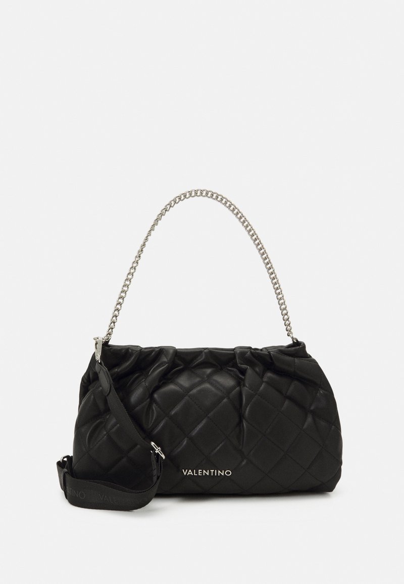 Borsa nera trapuntata in pelle lucida con manico a catena e tracolla regolabile. Presenta un dettaglio con logo sulla parte anteriore e una morbida apertura superiore arricciata.