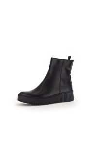 Botas de cuero negras hasta el tobillo con un diseño elegante, un leve brillo, cremallera lateral y suela de goma texturizada. Tacón apilado para mayor altura.