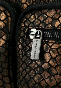 Materiale a motivo nero e rame con una texture rettile. Presenta una chiusura con zip dotata di un tirante metallico contrassegnato "COWBOYSBAG."