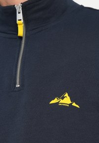 Marine blauwe zip-up pullover met hoge kraag, voorzien van een gele bergafbeelding en merknaam. Textuurstof met een gladde afwerking.