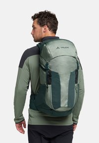 Sac à dos Vaude vert au design épuré, avec un devant texturé, des bretelles réglables et plusieurs poches. Construction en matériau durable.