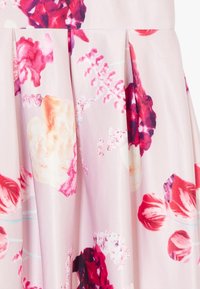 Gonna floreale con un tessuto rosa chiaro e vivaci motivi di fiori rossi e viola. Il design a pieghe aggiunge texture e movimento.