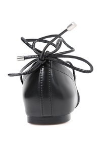 Bailarina de cuero negro con puntera redondeada, con finos cordones negros atados en forma de lazo en la parte posterior y un pequeño tacón apilado.