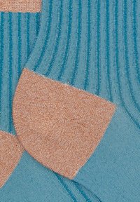 Calzini rivestiti color turchese con un motivo morbido color pesca sul tallone e sulla punta. Realizzati in un tessuto con una leggera lucentezza, presentano una texture liscia.