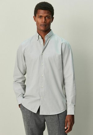 Camicia grigia chiaro con bottoni, colletto a punta e maniche lunghe, realizzata in morbido tessuto di cotone. Presenta una texture uniforme e dettagli di cuciture sottili.