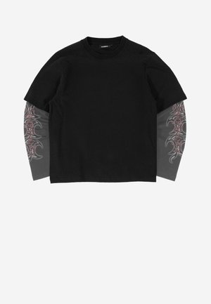 Must lühikeste varrukatega T-särk kantuna üle pika varrukaga halli läbipaistva kangaga, millel on varrukatel roosa ja musta hõnguga hõimukujundused.