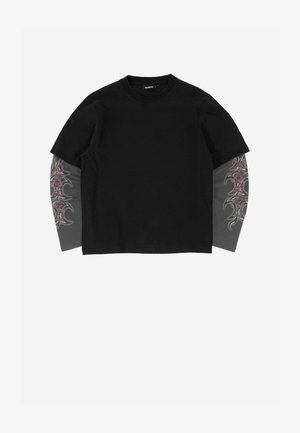 Must lühikeste varrukatega T-särk kantuna üle pika varrukaga halli läbipaistva kangaga, millel on varrukatel roosa ja musta hõnguga hõimukujundused.