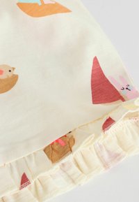 Tissu en crêpe doux avec petits oiseaux imprimés et un lapin rose, doté d'un bord froncé élastiqué.