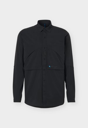 Fekete hosszú ujjú, gombos ing klasszikus gallérral és jellegzetes rétegezett zsebmintával a mellkason, egyszínű háttér előtt.