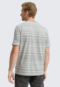 Chemise pour homme à manches courtes de couleur gris clair avec des rayures horizontales en gris foncé, bleu et vert. Tissu doux, col rond, coupe décontractée.