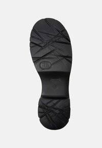 Semelle de chaussure en caoutchouc noir avec un motif de grip texturé, présentant un design en croisillons et des détails de taille en relief. Forme de orteil plate et arrondie.