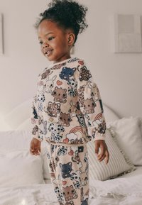Set di abbigliamento da casa per bambini in due pezzi, realizzato in morbido tessuto chiaro, con motivi di animali dei cartoni animati colorati, maniche lunghe e polsini elasticizzati.
