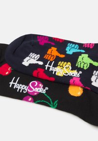 Črne nogavice z živahnimi vzorci rok in sadežev ter gladko teksturo. Ime blagovne znamke "Happy Socks" jasno prikazano v beli barvi.