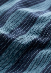Tissu tricoté présentant des rayures horizontales alternées de bleu clair et de bleu foncé, affichant une surface texturée avec un aspect ondulé.