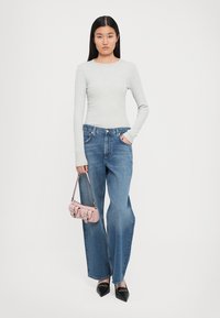 Light gray long-sleeve top, high-waisted blue wide-leg jeans, pink handbag with silver hardware, black pointed flats, minimalist design.