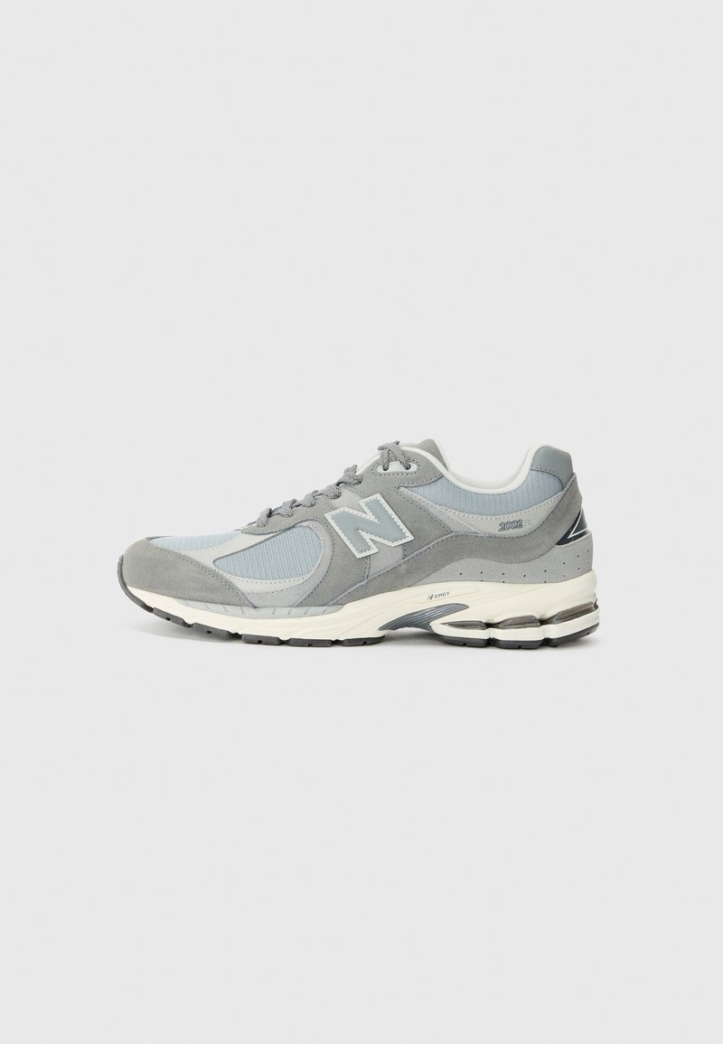 Light grey running shoe featuring mesh and suede materials, textured panels, a rubber sole, and a prominent "N" logo on the side.