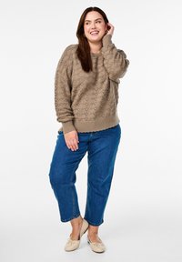 Beige knitted sweater with textured pattern, paired with blue cropped jeans and light beige ballet flats. Sweater has ribbed cuffs and hem.