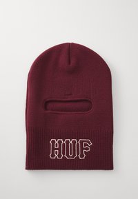 Burgunderrød strikket balaclava med horisontalt øyeåpning og "HUF" brodert i hvitt på den nedre fronten.