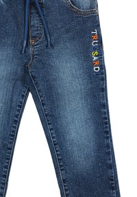 Jeans in denim blu scuro con taglio dritto, dotati di vita con coulisse e ricamo multicolore "TRUSSARDI" sulla coscia sinistra.