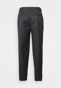 Black pinstriped trousers with an elastic waistband and a rear pocket. The fabric has a smooth texture and tapered leg design.