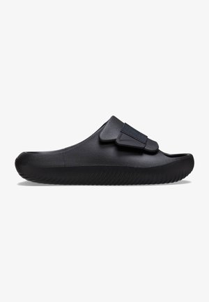 Black sandal made of smooth material; features adjustable Velcro strap and a textured, contoured sole with ridged detail.
