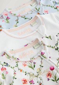 Tre body per neonati piegati con stampe floreali in colori pastello, ciascuno con cuciture rosa e marchio "Baker by Ted Baker" all'interno del colletto.