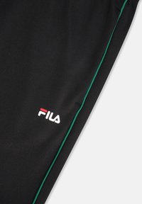 Svarta träningsbyxor med gröna sidopaneler. Har Fila-logotyp i vitt och rött. Tillverkade av ett mjukt, lätt tyg.